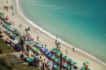 people walk on sand strip next to sun umbrellas on paradise summer beach. Aerial view