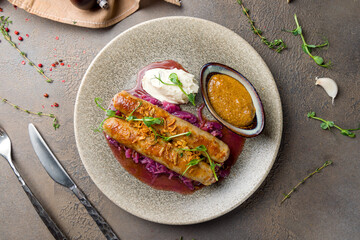 fried pork sausages on plate with sauce and coleslaw on brown table top view