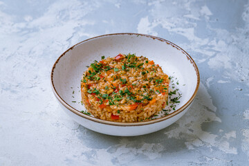 Rice with vegetables on plate on white concrete table