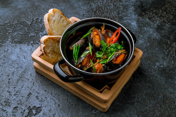 Mussels in tom yam sauce and chili peppers on black bowl