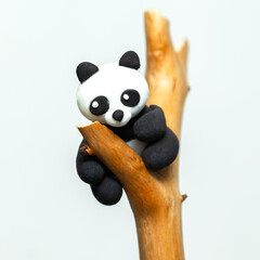 Plasticine panda hangs on a branch.