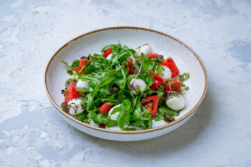 Caprese salad with mozzarella and tomato and greenery on grey concrete table