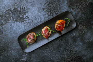 assorted bruschett on black plate on dark stone table top view