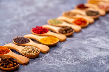 A set of spices on a gray background. Variety of spices from India. Food decoration design. Various spices, peppers and herbs close-up top view. Set of peppers, salt, herbs and spices for cooking.