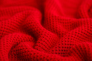 Knitted surface of woolen things as a background. Close-up of soft fabric red color knitted patterns texture. Warm winter clothing. Background textile surface with copy space for text.
