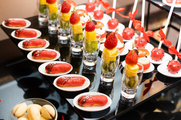 Candy bar. White wedding cake decorated standing of festive table with deserts, strawberry tartlet and cupcakes. Wedding. Reception Tartlets