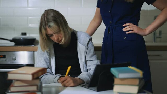 Teenage girl and her mother doing schoolwork at home.