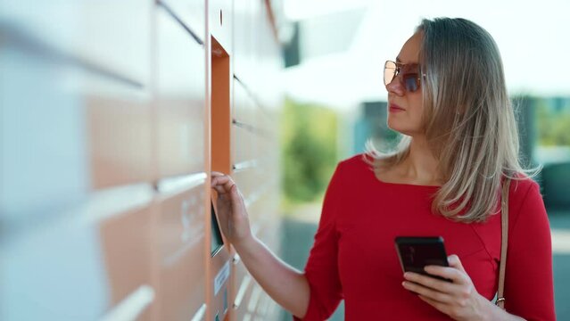 Woman entering code to pickup mail from automated postal machine.