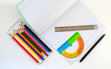 notebook pen ruler protractor and a set of colored pencils for drawing on a white background