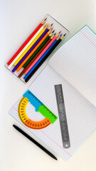 notebook pen ruler protractor and a set of colored pencils for drawing on a white background