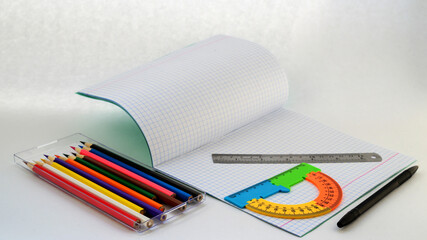 notebook pen ruler protractor and a set of colored pencils for drawing on a white background