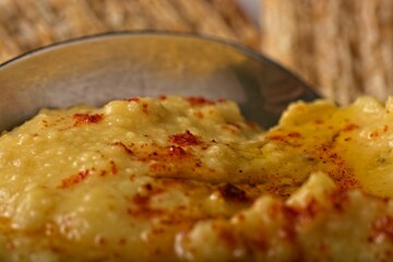 Close-up view of homemade hummus and serving spoon with olive oil and paprika garnish