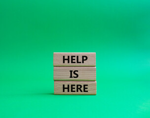 Help is here symbol. Wooden blocks with words Help is here. Beautiful green background. Business and Help is here concept. Copy space.