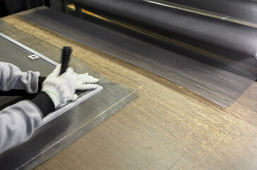 The worker's hand is blurred in motion. Mosquito net for windows during the assembly process.