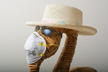 Wicker flamingo dressed in straw hat and sun glasses and N95
