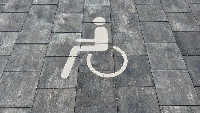 Large disabled parking lot white sign over brick pavement