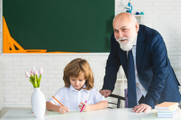 School boy grandson reading book and writing with old senior teacher grandfather.