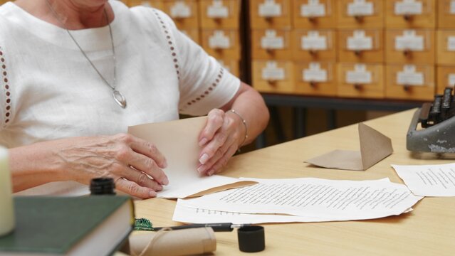 4K. An elderly woman writes a letter in the library