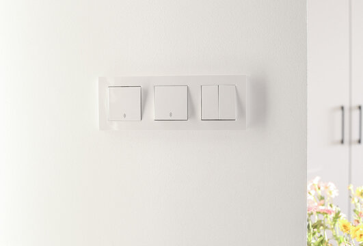 three different light switches on a white wall background. Electrical wiring in a modern house