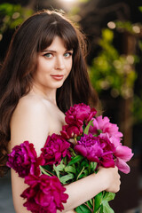 Naklejka premium an beautiful woman with long hair and bare shoulders and a bouquet of peonies
