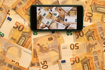 Money paper 50 euro banknotes on the background of a smartphone screen, the concept of business, investment and income growth. Mobile banking and finance concept