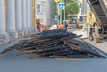 Dump of metal structures - fence, curbs - on the main street of the city, road repair