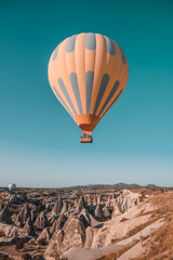 Fototapeta na wymiar One orange hot air balloon in blue morning sky