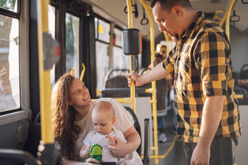Parents riding a bus with their child during a day.