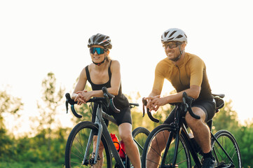 Happy couple riding road bicycles and taking a break during a sunset