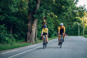 Couple riding road bicycles outside and wearing helmets and sunglasses