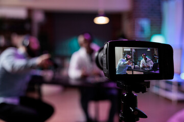 Content creator using camera to record podcast conversation, filming talking show discussion in...