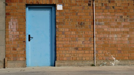 sidewalk with red brick wall and blue door