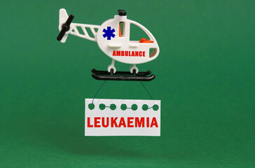 On a green surface, an ambulance helicopter with a sign - LEUKAEMIA