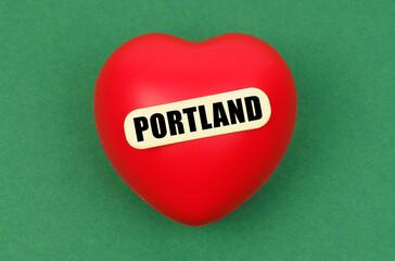 On a green surface lies a red heart with the inscription - Portland