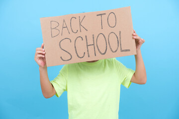 funny boy hides his face with a back-to-school poster