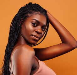 pretty young african american woman with braids posing cheerful gesturing on brown background, lifestyle people concept