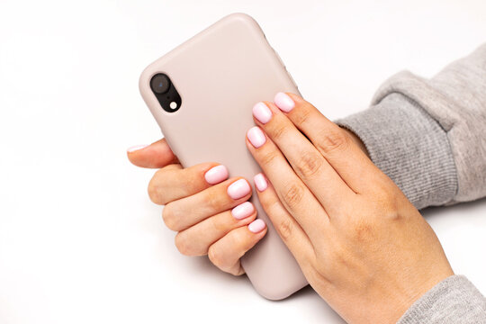 Manicured Female Hands With Stylish Light Pink Gel Nails Holding Mobile Phone. Trendy Modern Design Nails Manicure. Skin And Nail Care. Beauty Treatment And Wellness. Trendy Colors. Close Up