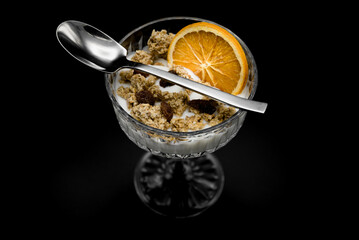 A healthy breakfast, lunch or snack with dairy, granola, raisins and a slice of candied orange.