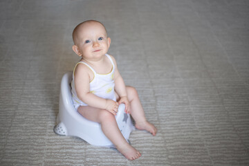 Cute baby in a diaper sitting on a potty. Toilet and potty training. A small child gets used to a...