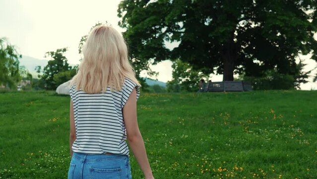 blond Caucasian girl walking in the beautiful green nature, medium shot. High quality 4k footage