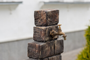 Antique bronze water faucet on a wooden stand installed outdoors - drinking water, washing hands,...