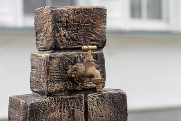 Antique bronze water faucet on a wooden stand installed outdoors - drinking water, washing hands,...