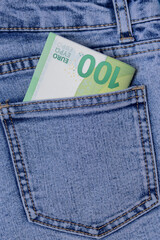 Several denominations similar to euros without numbers in the back pocket of jeans on a blue background - vacation fees, a trip abroad on a trip