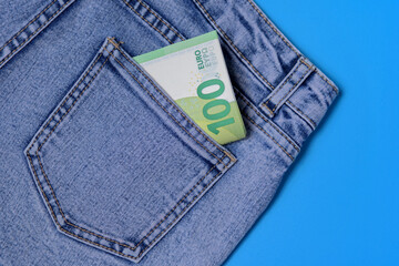 In the back pocket of blue jeans, 100 euro banknotes are folded in half - vacation pay, trip abroad...