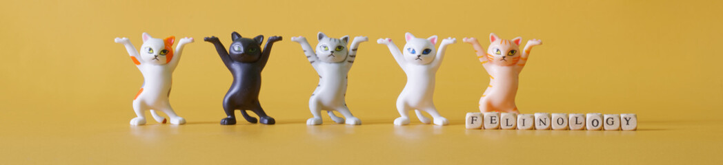Funny toy dancing meme kittens, notepad, pen and magnifier on yellow. Concept of a didactic game about school. Readiness for beginning of the school year and school lessons. Selective focus. - obrazy, fototapety, plakaty