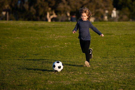 Sports kid during soccer training. Soccer boy, child play football. Kid kicking a football ball on a grass.