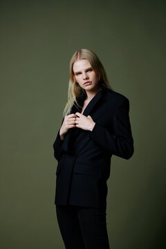 A Concept For Marketplaces And Clothing Brands. Full-length Portrait Of A Blonde Holding A Jacket Collar Posing On A Green Background In The Studio