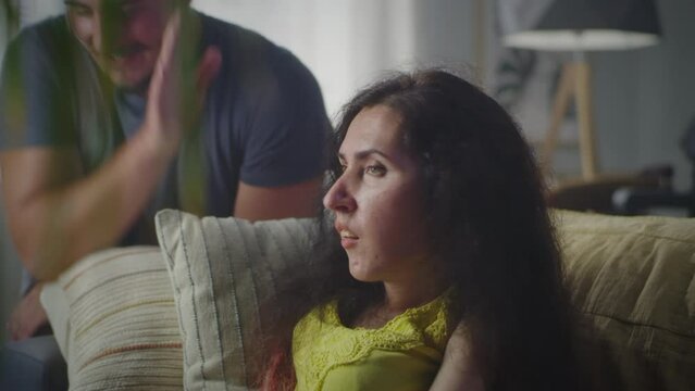 Confused woman with a disability sitting on a couch and talking with nervous man while they arguing and having quarrel