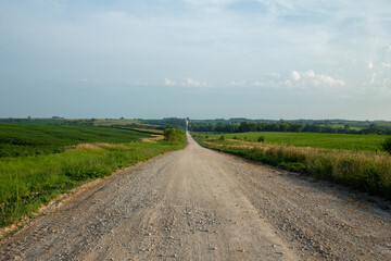 Long lonely dirt country road near sunset in midwest USA near Texas and Oklahoma in rural countryside surrounded by farms and farmland - obrazy, fototapety, plakaty