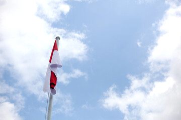 Indonesian flag on pole against blue sky